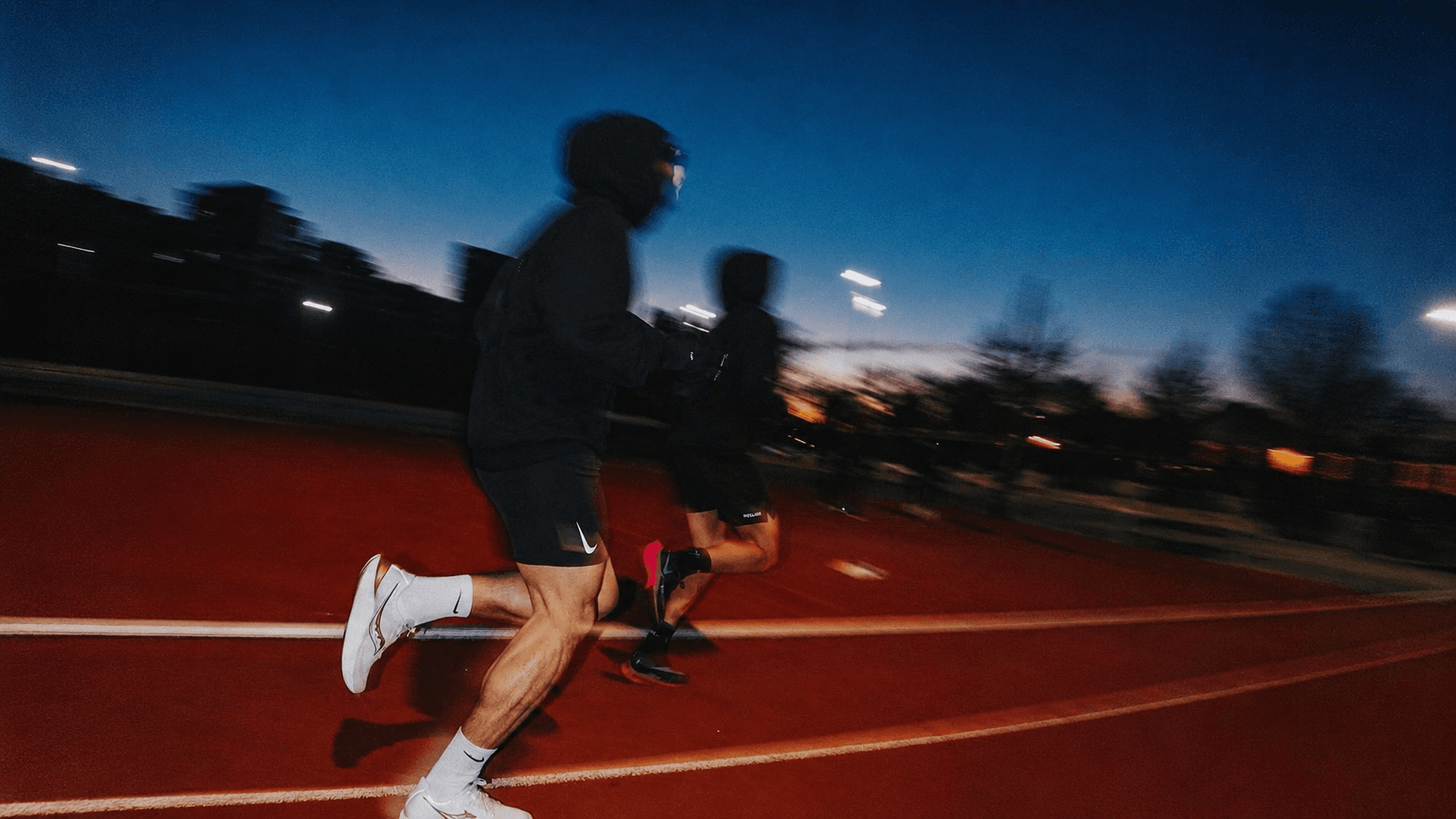 Two people running at dawn on a track